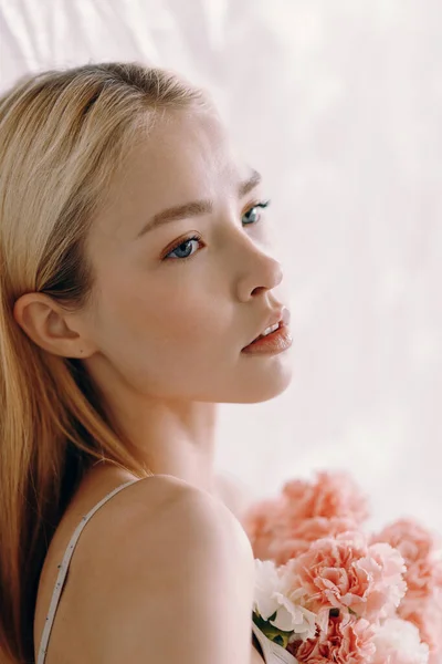 Beautiful blonde in beige underwear with carnations. Body care, beautiful figure of a girl, flowers growing from a person. — 图库照片