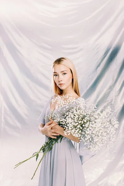 Portrait of a young beautiful girl in polyethylene with flowers on the background. Fashion portrait, environmental agenda. — Stockfoto