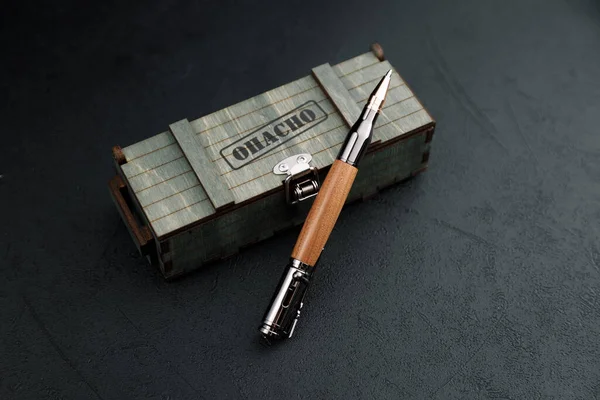 Un conjunto de costosos bolígrafos militares en cajas de madera, composiciones sobre un fondo oscuro con atributos. Bolígrafo regalo lujo. Fotos De Stock