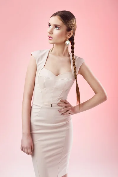 Porträtt av en attraktiv ung brunett tjej well klädd med fläta mot rosa bakgrund — Stockfoto