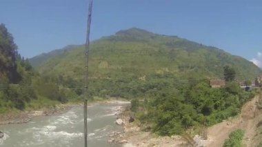 Su kaynağının yakınındaki köprüden geçerken ve Flora 'nın arkasında dağlar varken sağdan sola kayarken. 