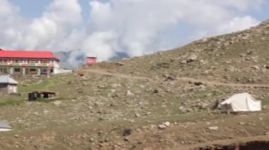 House Near Tents And Trucks In Mountains - Slide And Pan - Up Left To Down Right 