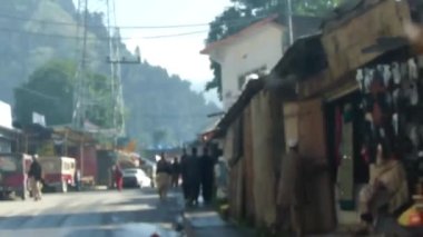 Passing By Men And Trucks Near Houses In Street - Slide Forward