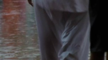 People Walking Barefoot Under The Rain In The Street - Static