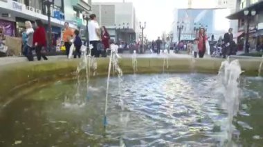 Çeşmeden su fışkırıyor, insanlar arkadan dolanıyor, soldan sağa doğru..