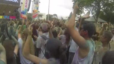 Crowd Covered By Colorful Powder Raising Hands In The Air In Rythm - Pan - Left To Right.