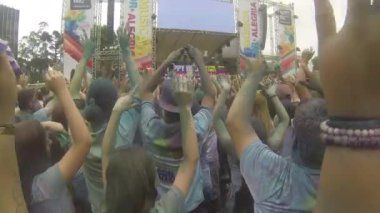 Crowd Covered By Colorful Powder With Hands In The Air, Jumping And Dancing - Handheld, Then Pan Left To Right, Then Right To Left.
