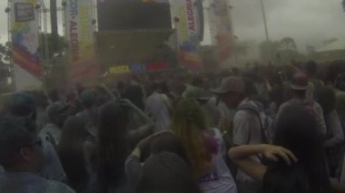 Dancing Crowd Covered By Colorful Powder In Front Of Stage - Pan - Left To Right.