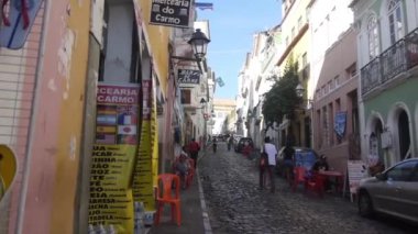 Yürüyen ve motosikletle küçük kaldırım kaldırımlarından geçen insanlar statik ve hafif sağa sola kayıyor.