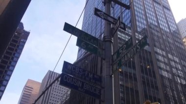  Road Direction Sign In Front Of Buildings From Below - Slide Right To Left And Pan Left To Right.