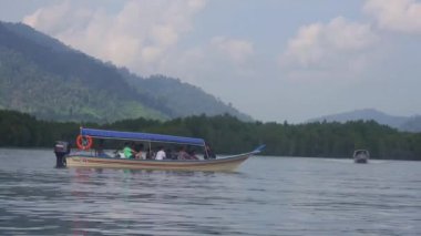 Boat With Tourists On Water Source Surrounded By Flora On Mountains