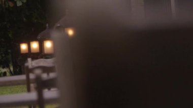 Sandalyelerin ve masaların arkasındaki bahçede dizilmiş fenerler.