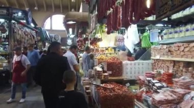 Kapalı markette yiyecek satan insanlar durağan ve hafif sağa sola kayıyor.