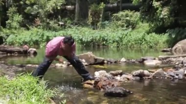 Adam nehirde yüzünü yıkıyor.