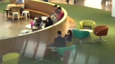 İnsanlar yemek katında oturup küçük toplantılar yapıyorlar.