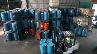 Bir fabrikadaki fıçılarla dolu rafların yakınındaki çatallı asansörler.