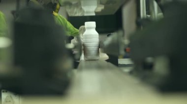 Yüzü Maskeli Fabrika İşçisi Koşu bandına Beyaz Şişe Koyuyor