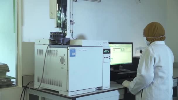機械の近くのコンピュータで働く茶色のヒジャブを持つ女性科学者 — ストック動画