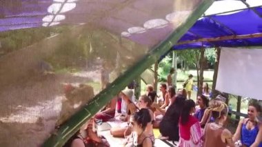 İnsanlar doğada büyük bir çadırın altında meditasyon yapıyorlar.