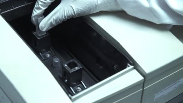 小さな透明な鍋を機械に入れる科学者 — ストック動画