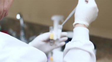 İşçi dikkatle şişelere kimyasallar sokuyor.