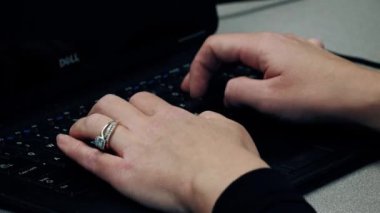 Güzel bir yüzükle siyah bir dizüstü bilgisayarda yazan kadın işçi eli.