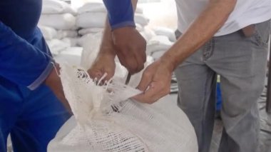 Depoda kocaman beyaz bir kakao torbası açan bir adam.