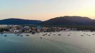 A Small Fishing Island With Mountains and Boats in Front - Static