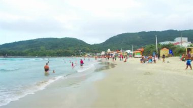  Sahilde, arkasında yeşil tepeler olan insanlar..