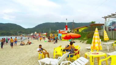  İnsanlar sahilde oturuyor ve sarı sandalyelerde dinleniyorlar.