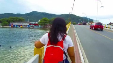 Köprüden aşağı doğru yürüyen kırmızı çantalı kadınlar