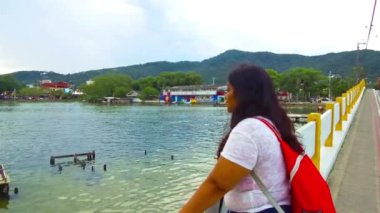 Köprüden göle bakan kırmızı çantalı kadınlar.