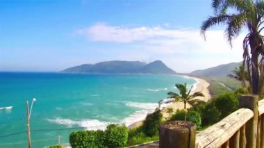 Beautiful Landscape View of a blue brazilian beach with mountains and palm trees - Slide - Left