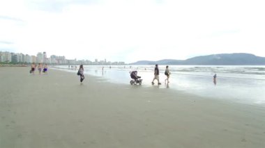 Kumsalda bebek arabası olan bir aile..