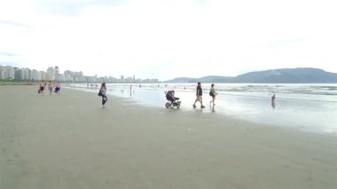 Kumsalda bebek arabası olan bir aile..