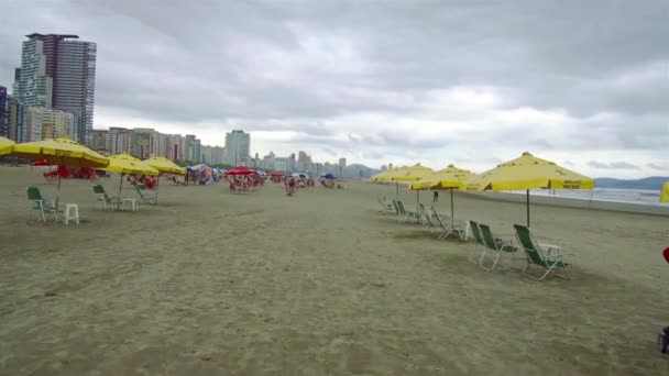 Прогулка Большому Песчаному Пляжу Желтыми Пумбреллами Рядом Городом — стоковое видео