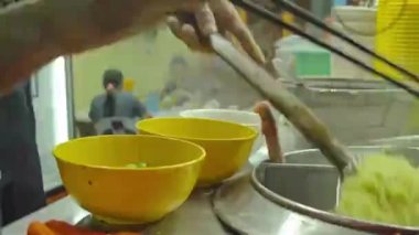 Asian guy preparing and cooking noodles for soup - side view - glide