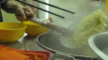 Asyalı adam çorba için erişte hazırlıyor ve çeviriyor.