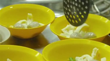 Tepside sarı ve beyaz bardaklarda taze etli şehriye hazırlayan adam..