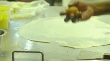 Hintli bir adam bir yumurta kırıyor ve Kuala lumpur 'da güzel bir restoranda roti canai için hamur döküyor..