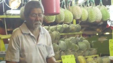 Old Chinese uncle packing durian for take away at a stall at a night market in Kuala lumpur 