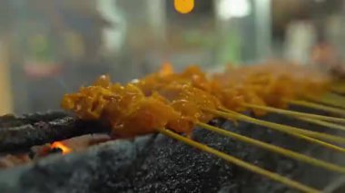 asian man making delicious bbq satay at a night market in kuala lumpur