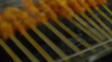 raw satay sticks being cooked on a bbq grill at a night market in malaysia