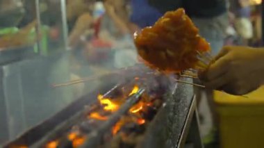 man putting fresh delicious bbq satay at a night market in kuala lumpur