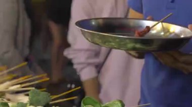 Man holding a silver plate with sausages at a steam boat stall