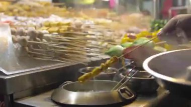 Gece pazarındaki buharlı tekne tezgahında kaynayan bir tencereden yiyecek çıkarmak..