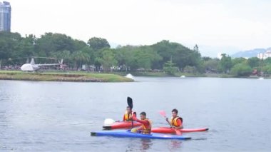 Malay çocukları Kuala lumpur 'daki Tiwangsa parkında bir gölde kayak yapıyor..