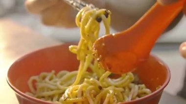 Chinese man eating dry beef noodles from red bowl
