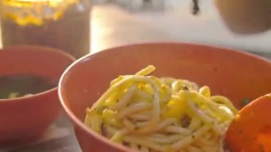 dry beef noodle being mixed with chopsticks - closeup - side view.