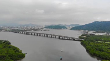  Adanın yakınındaki denizin ortasındaki uzun bir köprünün havadan görünüşü ve Santos şehrinin manzarası..